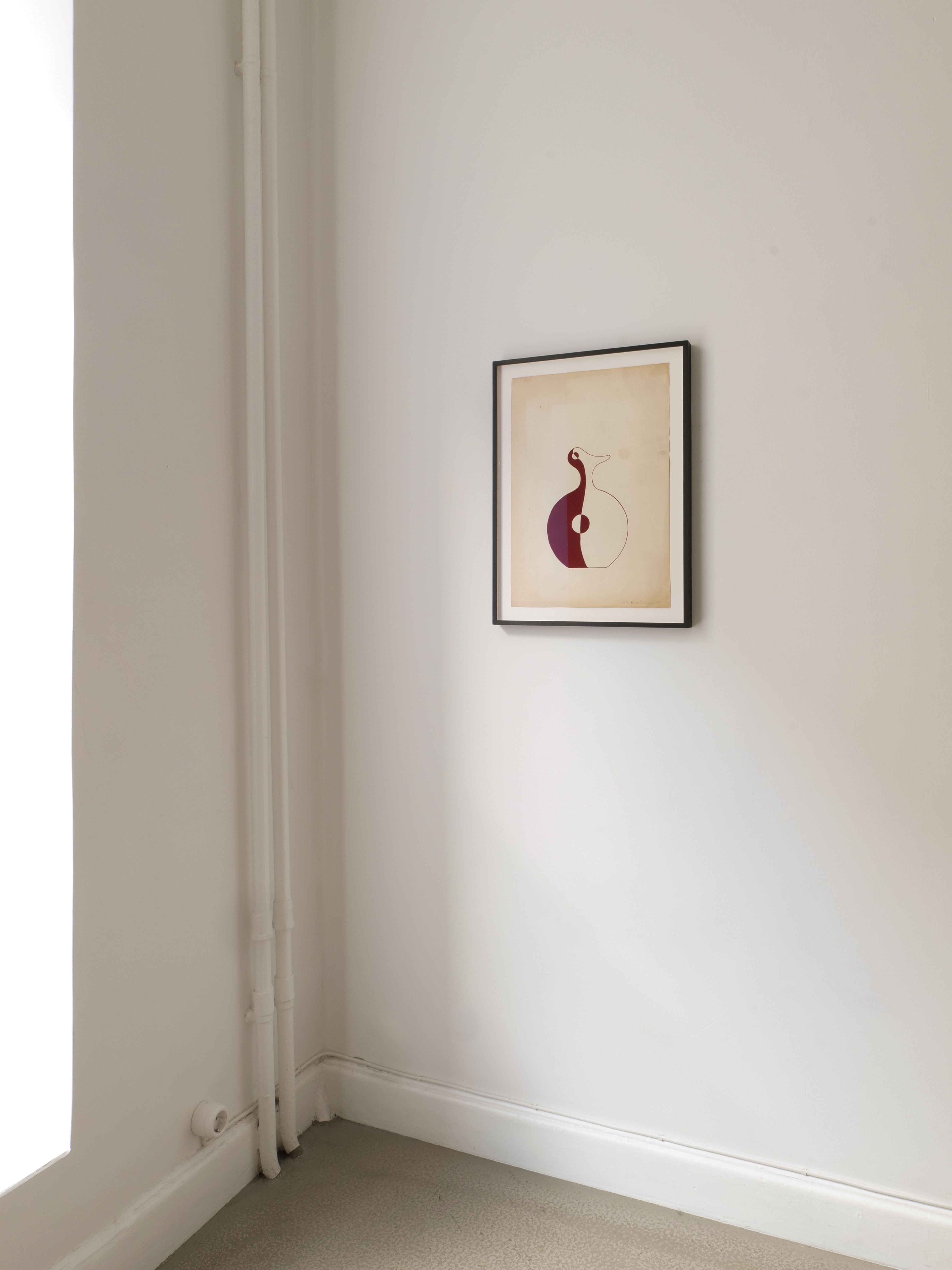 A minimalist room with white walls features a framed 'Red Vase' Painting 1951 by Collection apart, with maroon and cream shapes, hanging near a corner with exposed vertical pipes.