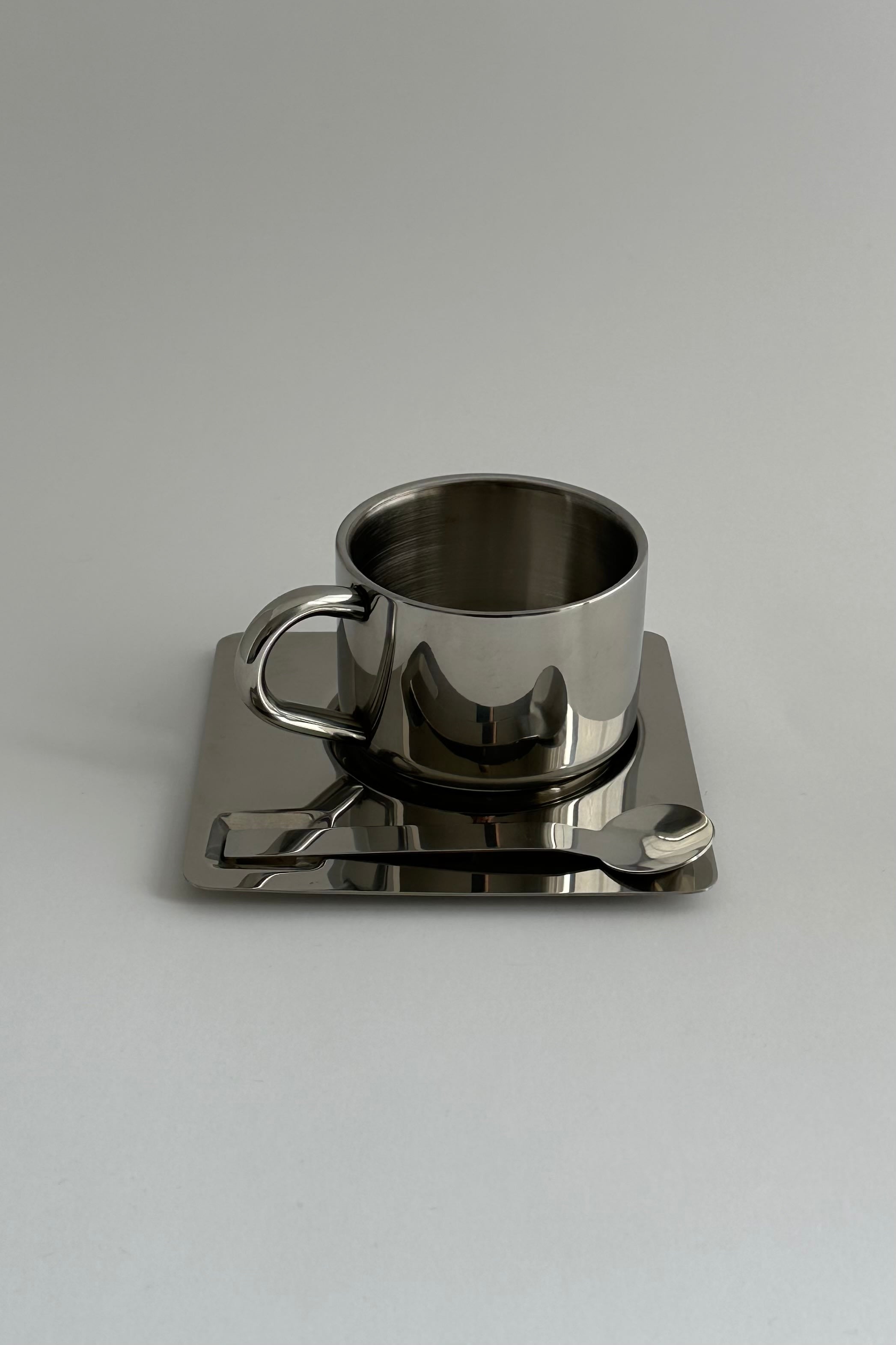 'HEDONISM' stainless steel cup with saucer — in context