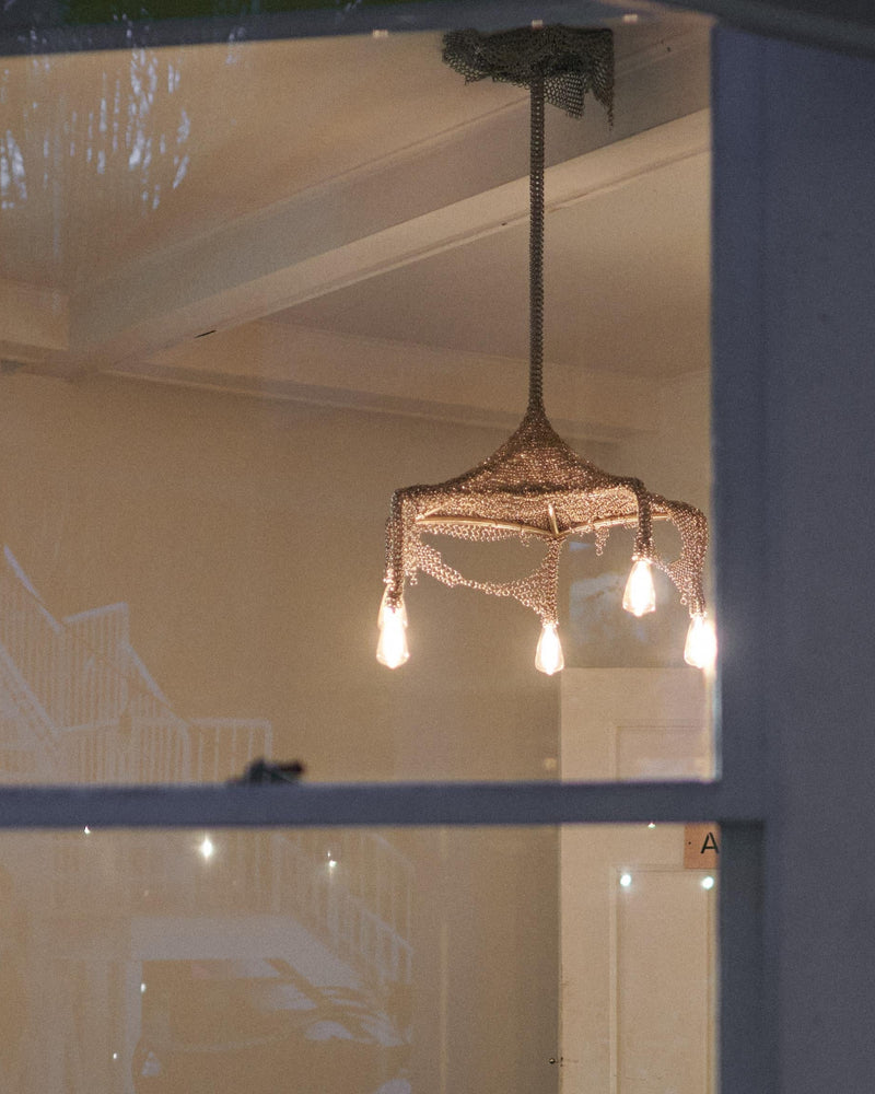 Chainmail Cobweb Chandelier - Pendant Light in Metal and Steel — view from outside showing warm light bulbs
