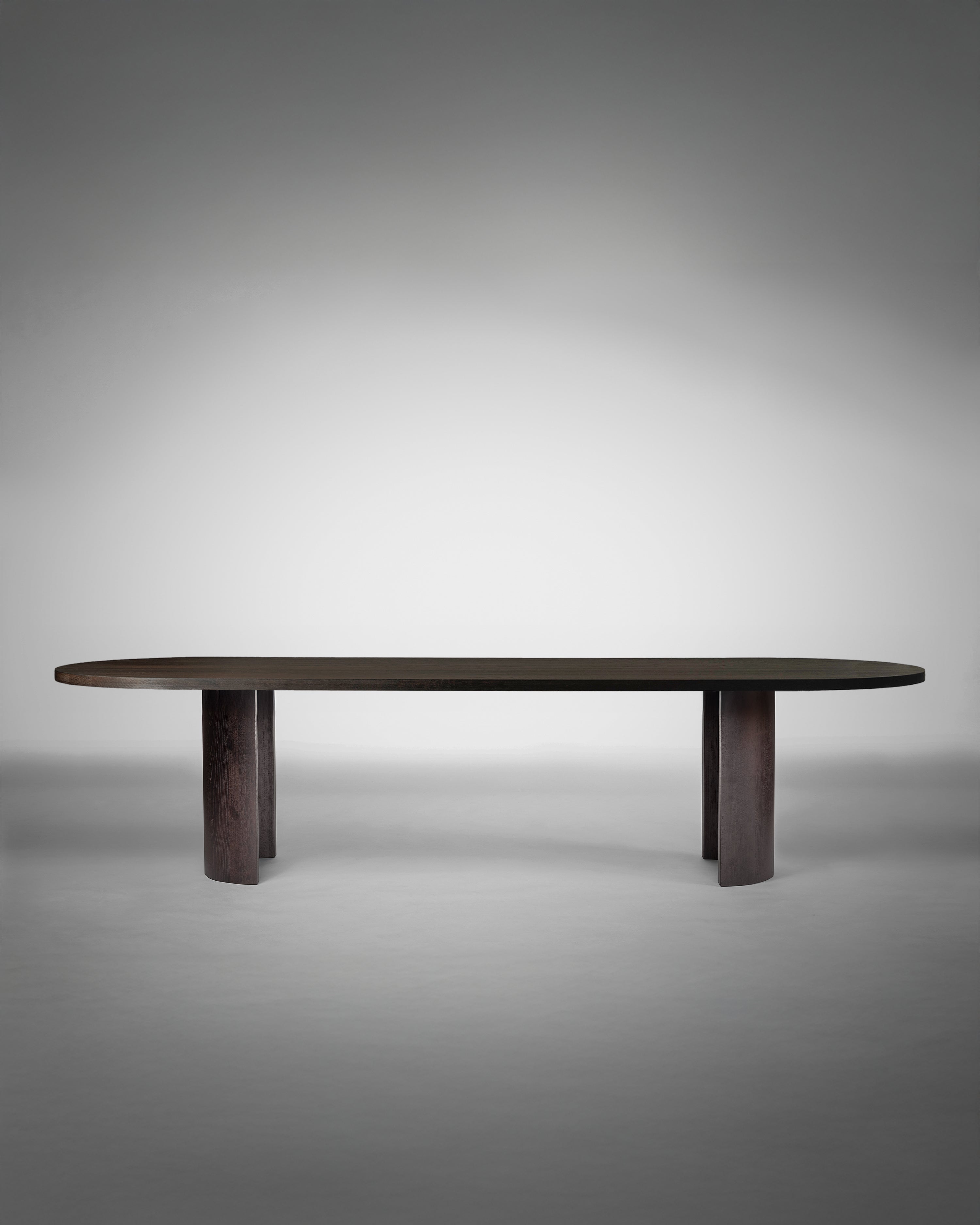 Aperta Capsule Table - Single Base — side angle showing dark wooden surface