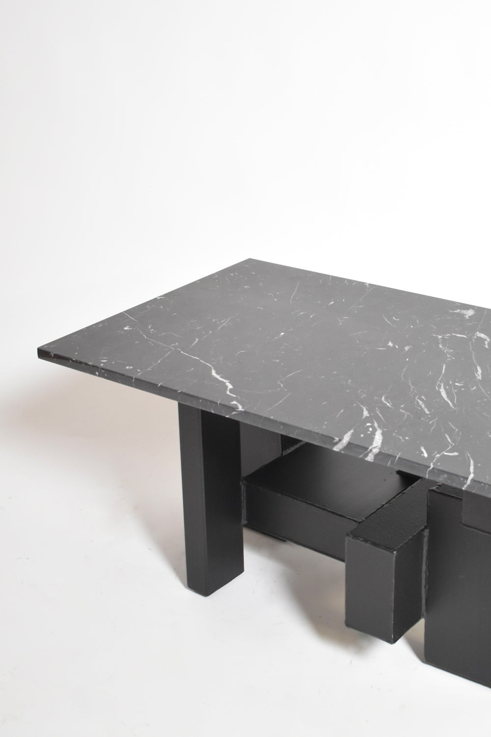 The Cubist Iron and Marble Coffee Table by Barracuda Interiors (1980s) features a black marble top with white veining and geometric block-style iron legs, shown on a plain white background.