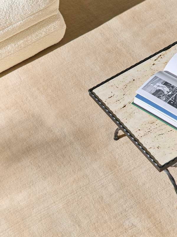 Hand-woven Rug in New Zealand Wool, Beige Sand — close-up on soft texture with coffee table