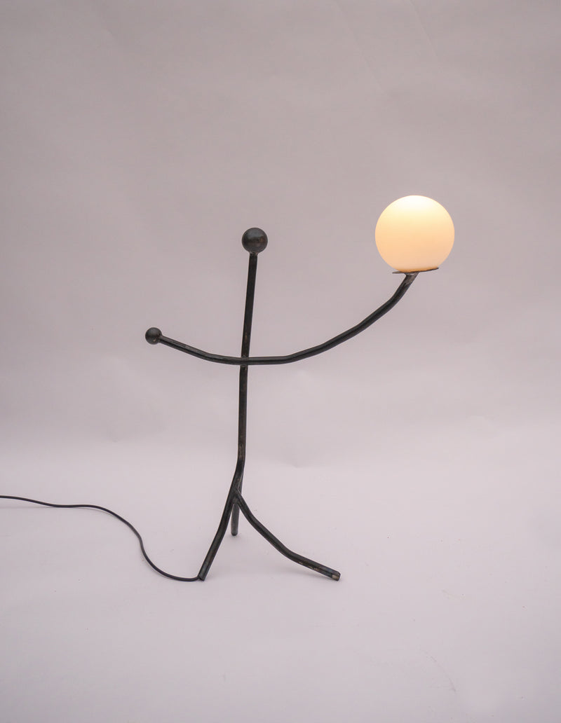 Balancing Act table lamp with illuminated sphere on black metal figure