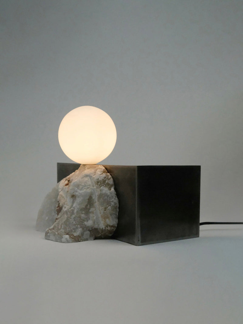 Modern table lamp with illuminated sphere, raw stone and black metal cube base
