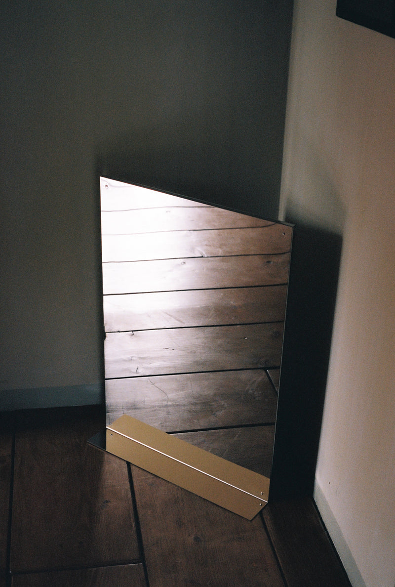 Large flat mirror reflecting wooden floor at angle in modern interior
