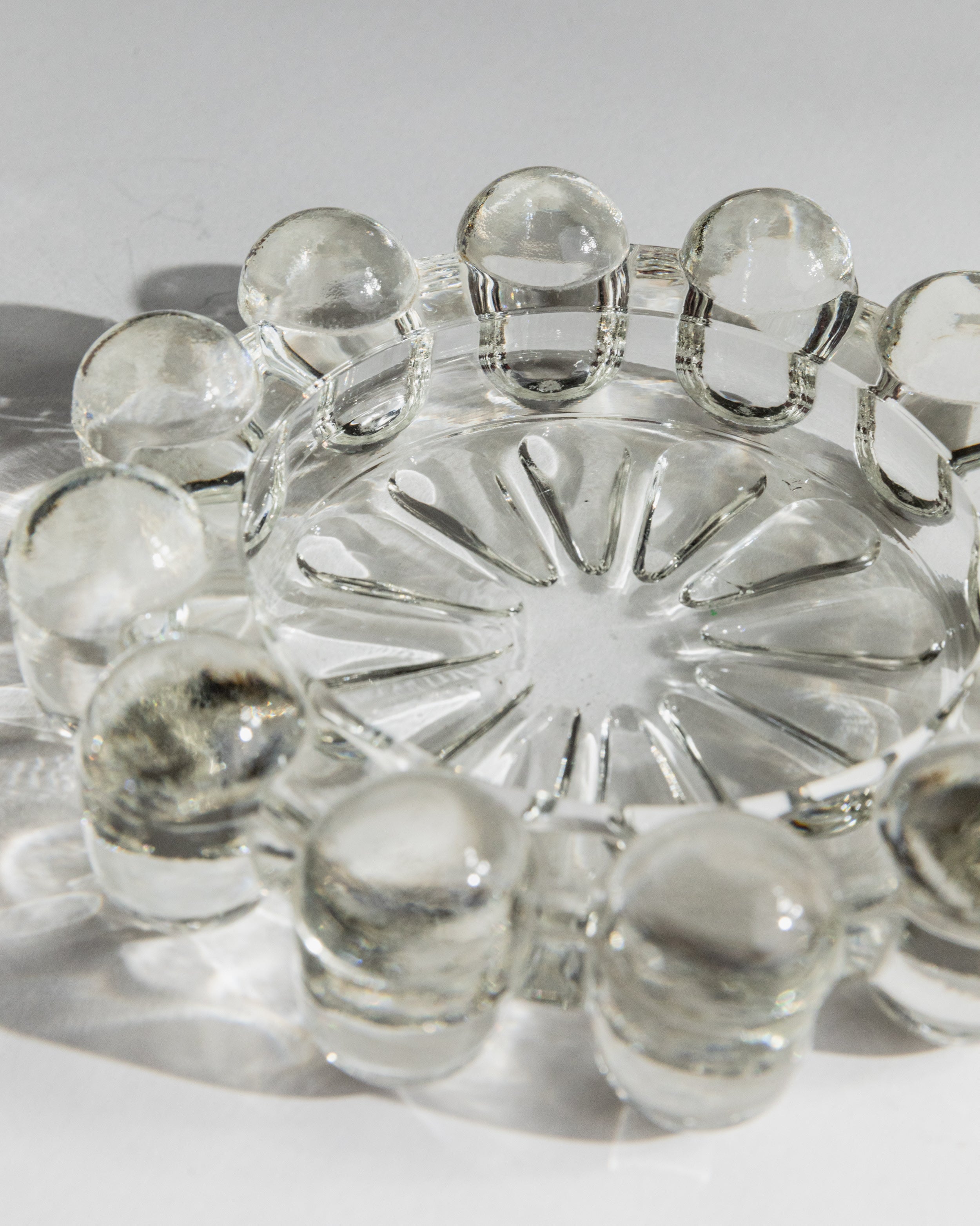 Clear glass ashtray with radiating star pattern and scalloped rim