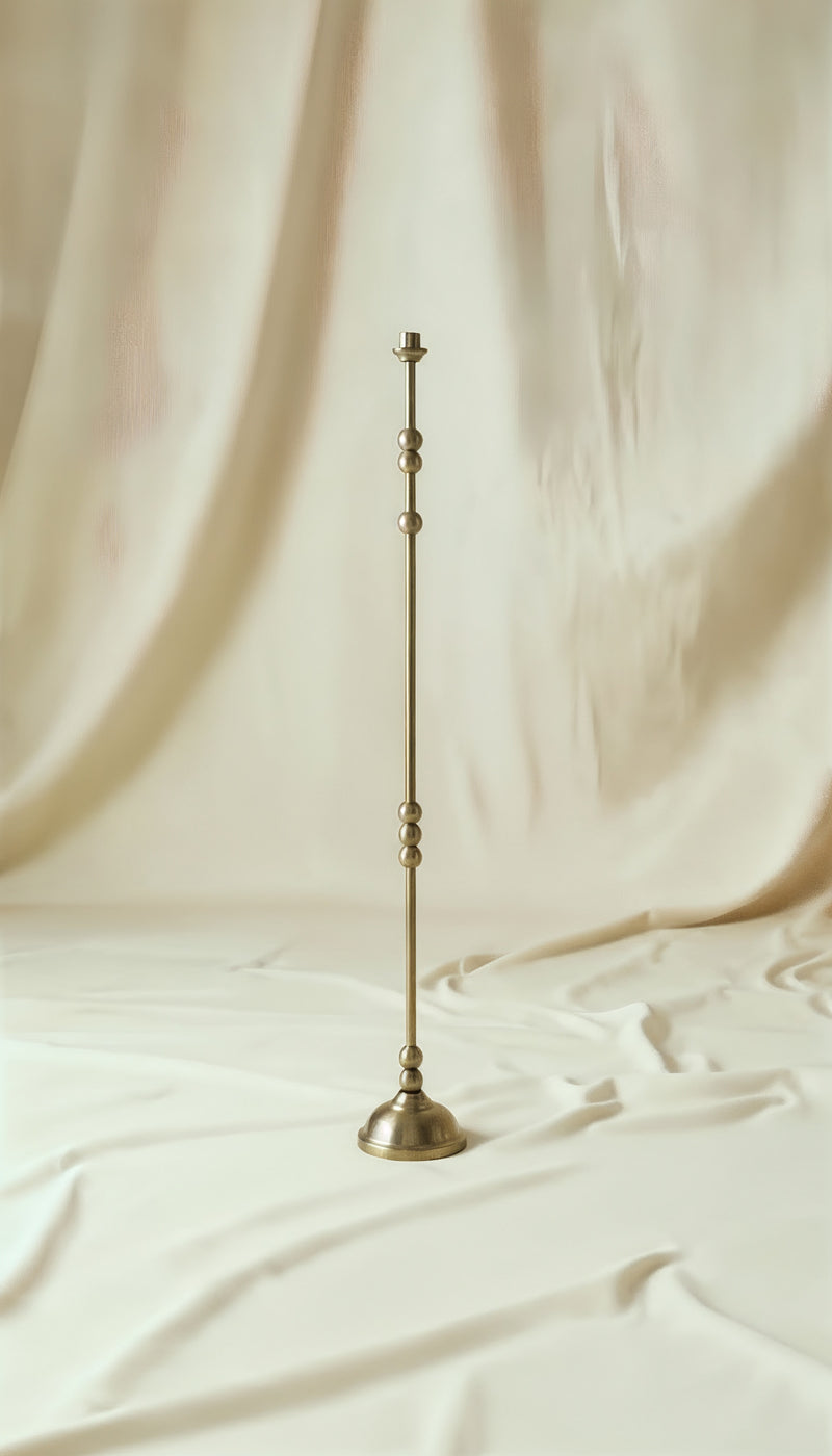 ASHA I – Brushed Brass Sculptural Candlestick Set — close-up of tall brass candlestick on soft fabric