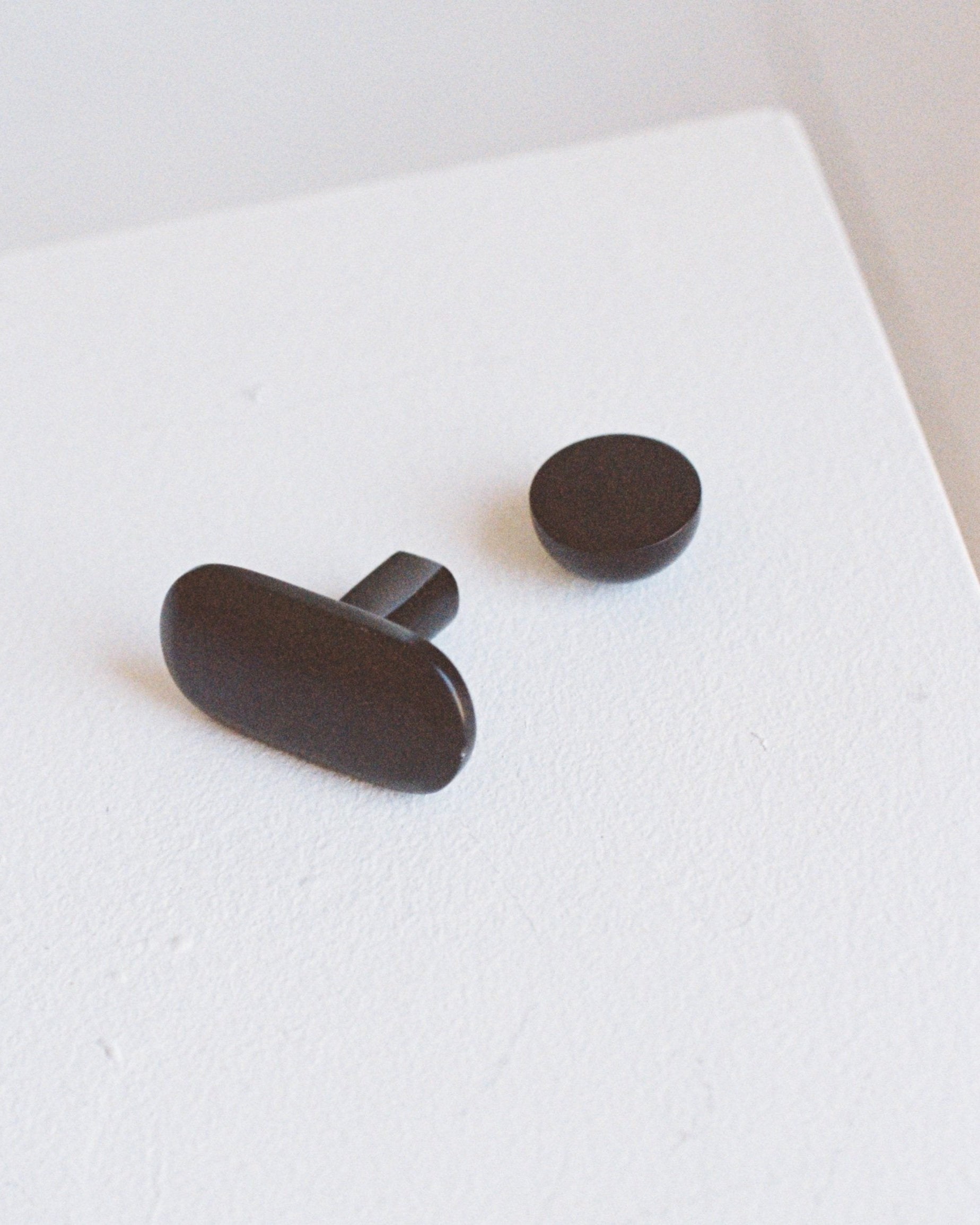 OVAL Cabinet Knob/Wall Hook — black metal knob on white surface