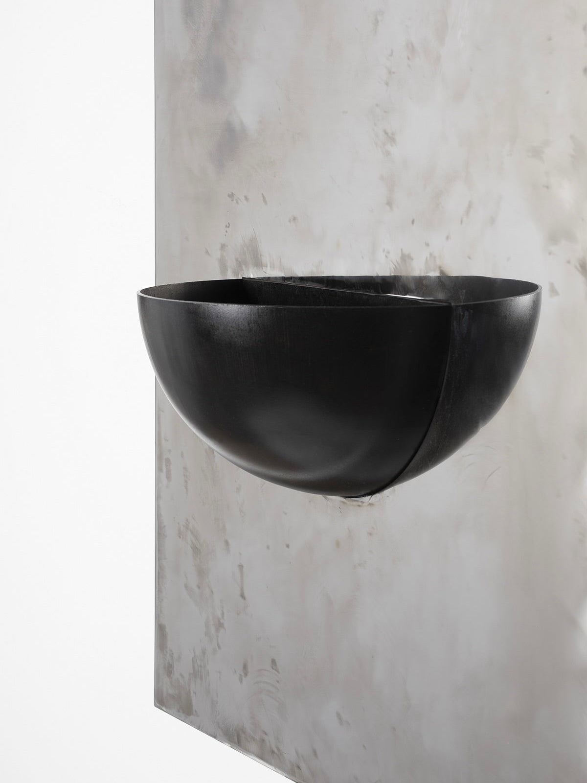The Mirror of Simple Souls (Large) - Contemporary Mirror in Steel — angled view against textured wall