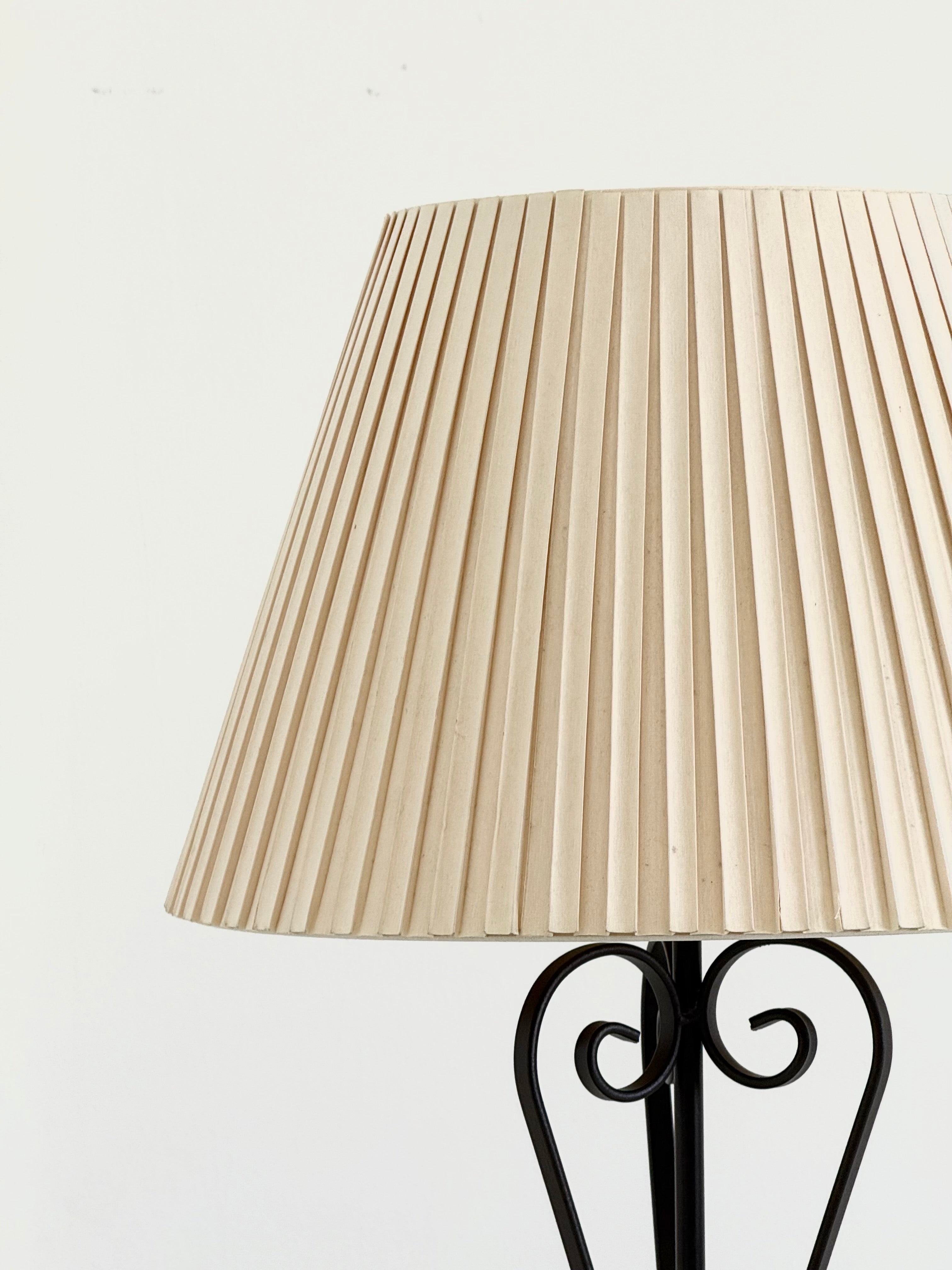 Vintage wrought iron table lamp in a swirl shape with a pleated shade — in context