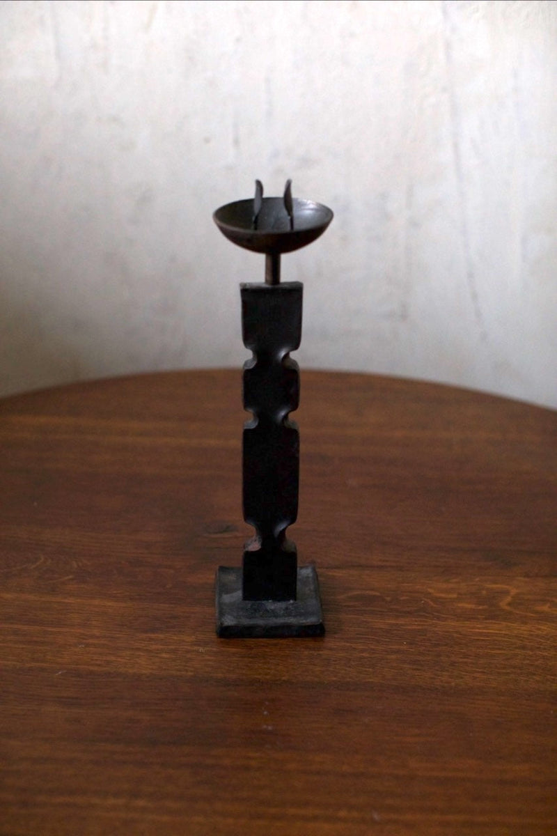 Brutalist Candleholder — close-up of black metal design on wooden table