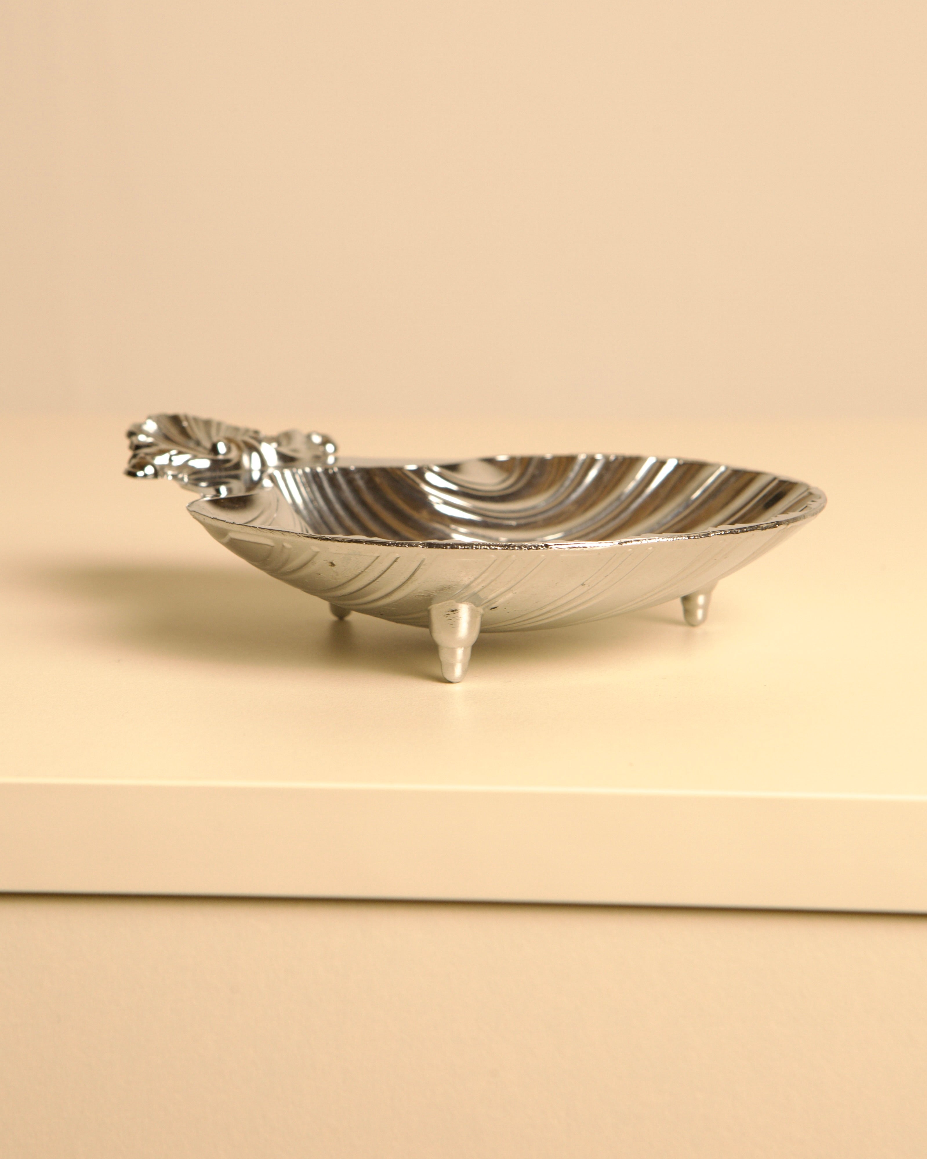 Silver-plated shell dish with decorative handle and three legs
