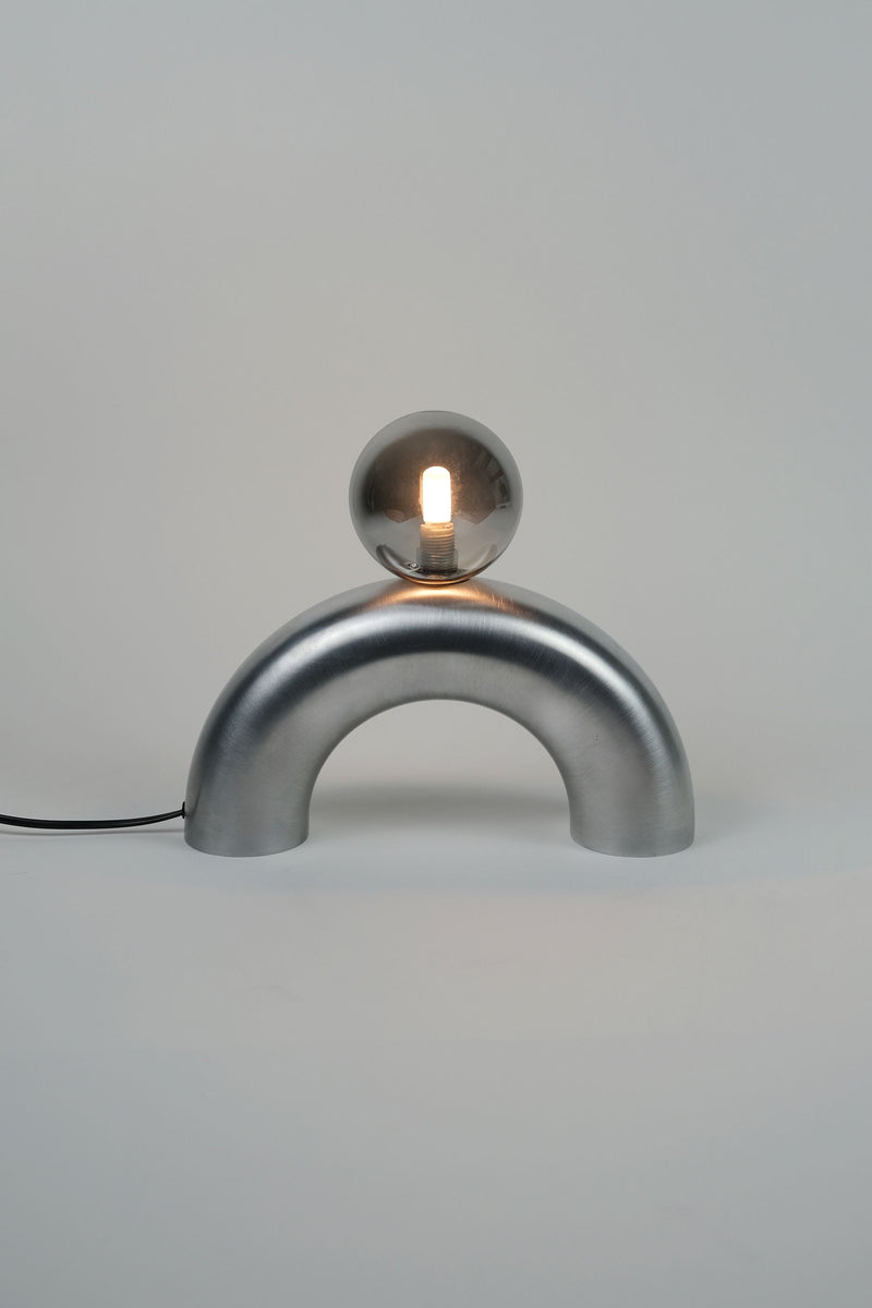 Modern aluminum arc table lamp with illuminated glass sphere on curved base