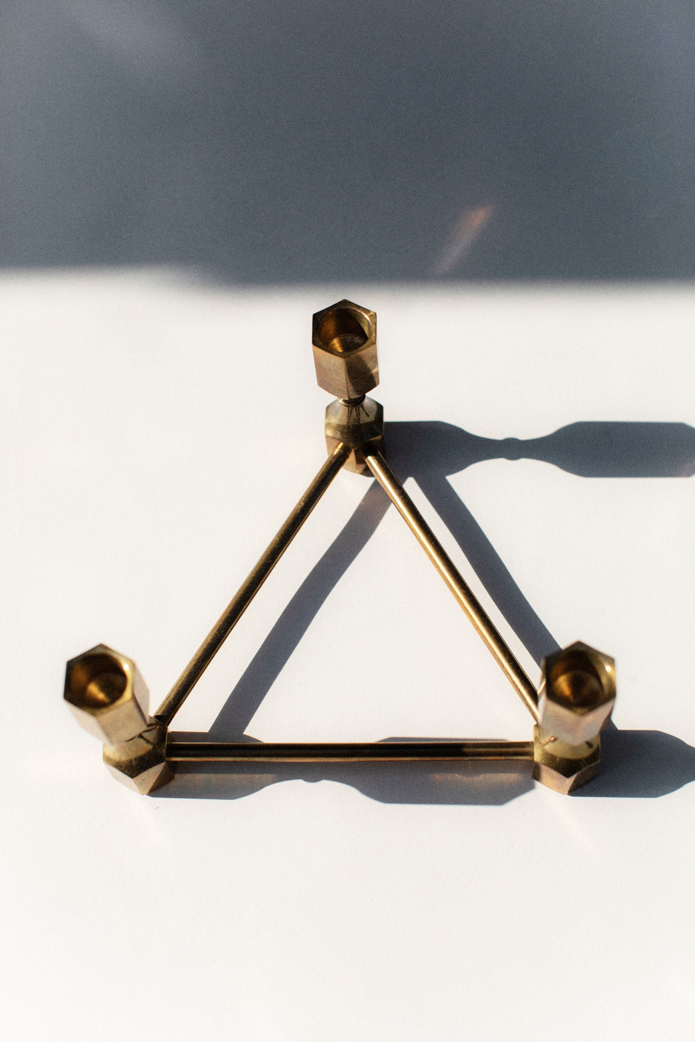Geometric brass candleholder with triangular base and cylindrical holders