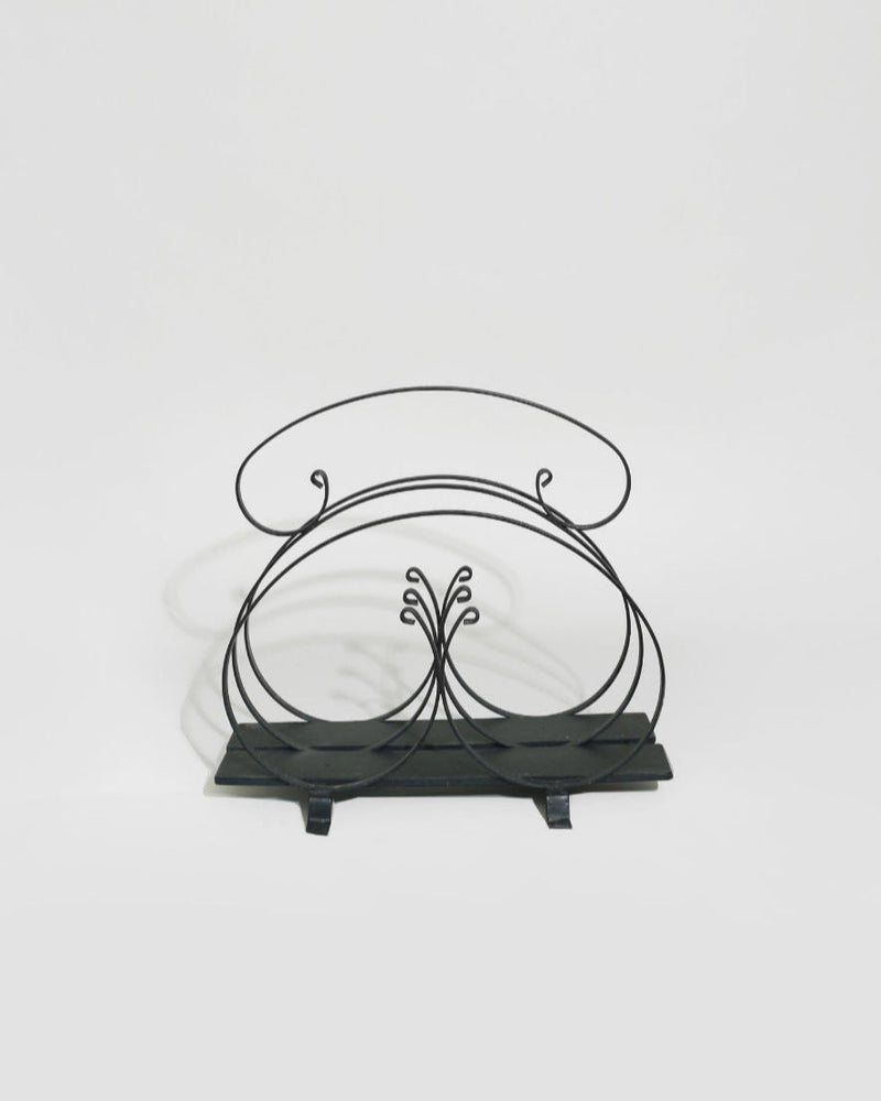 Elegant black iron magazine rack with decorative scrollwork design