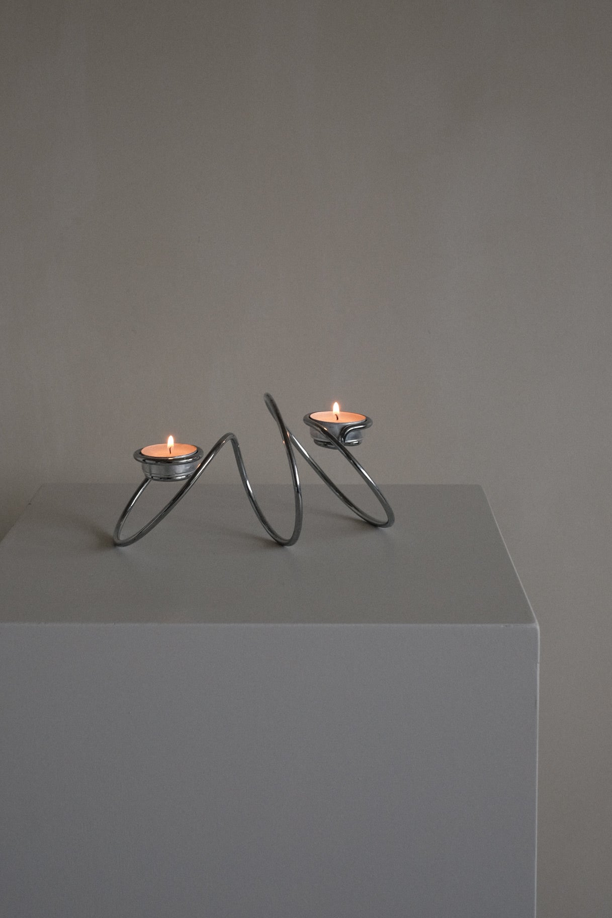 Chrome Candleholder — top view on minimalist pedestal with candles lit