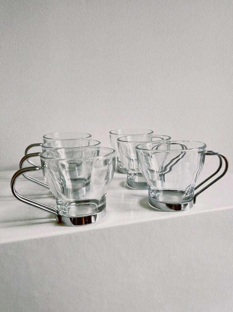 Set of 6 clear glass espresso cups with metal handles on white surface