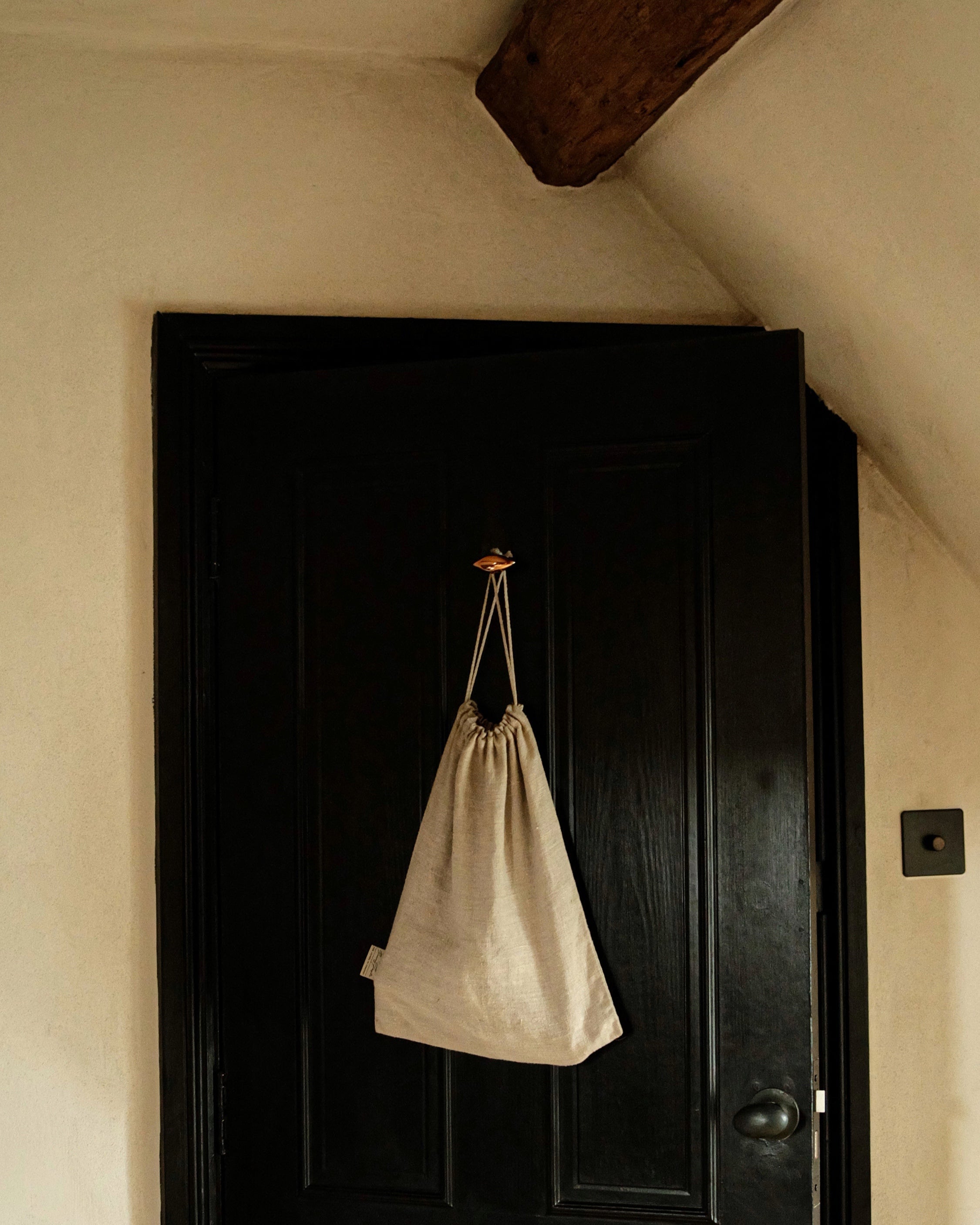 GOOD EYE Cabinet Knob/Wall Hook — mounted on black door holding linen bag