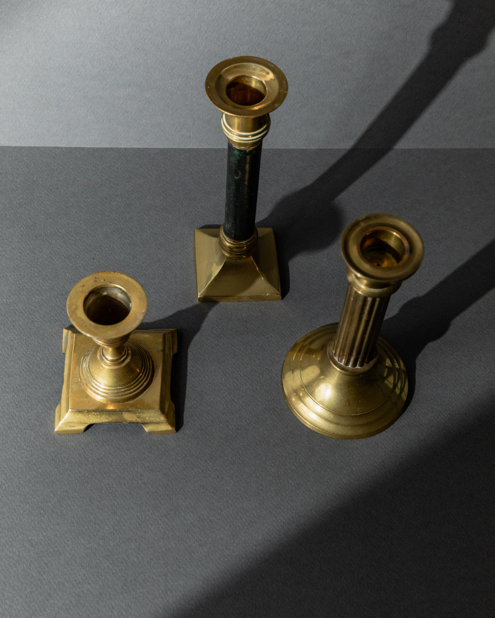Vintage 1940s Brass Candleholders Set of 3, Mixed Shapes, Classic Antique Design — top view on gray background