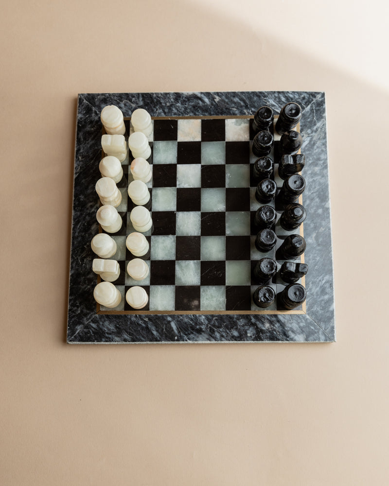 Vintage marble chess set with carved pieces on checkered stone board