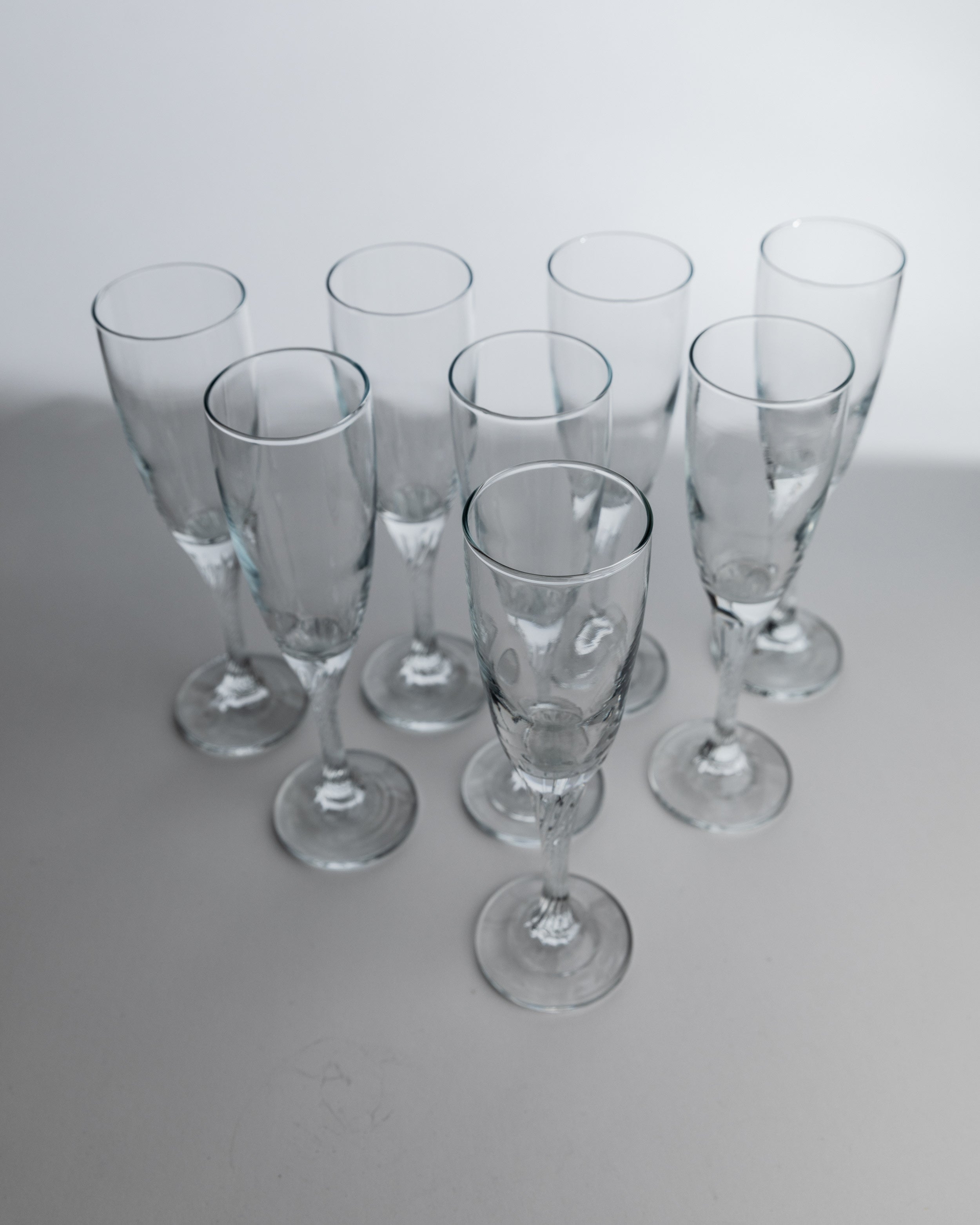 Eight 1980s crystal champagne flutes arranged on white surface