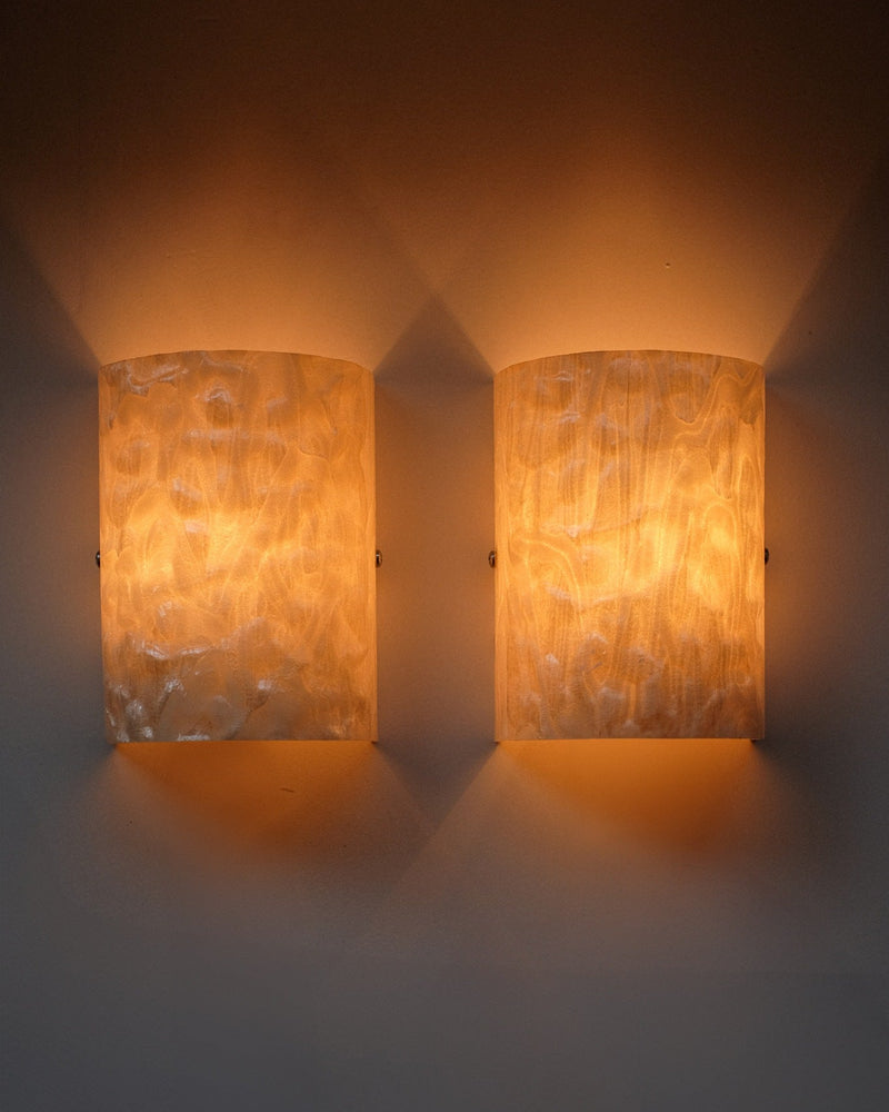 The Set of 2 Mother-of-pearl Wall Lamps by septembre studios features textured, translucent surfaces that emit a warm, soft glow for a cozy, inviting ambiance against any plain wall.
