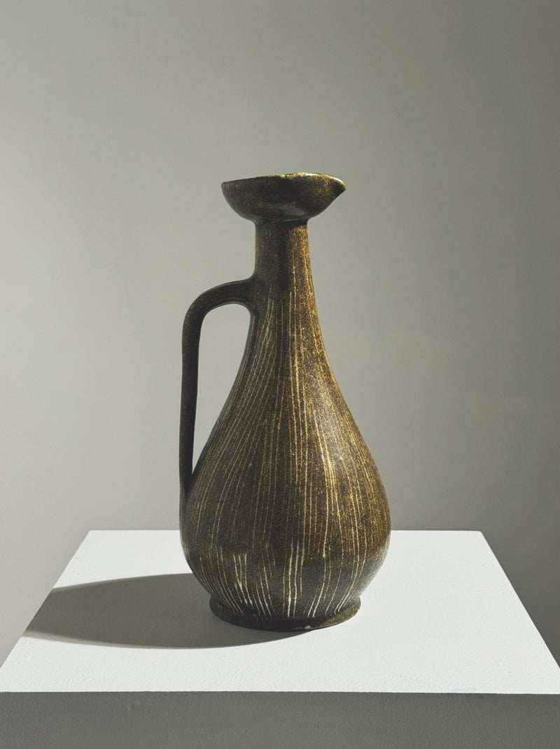 Dark ceramic pitcher with ribbed texture and golden highlights by Accolay Potters
