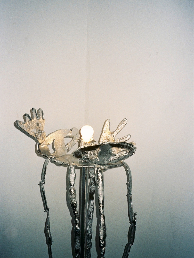 Sculptural bronze floor lamp with organic metallic forms and glowing bulb
