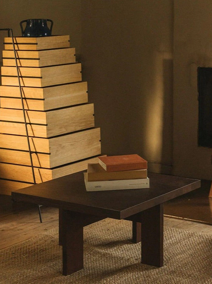 Dark oak square coffee table with stacked books in modern interior