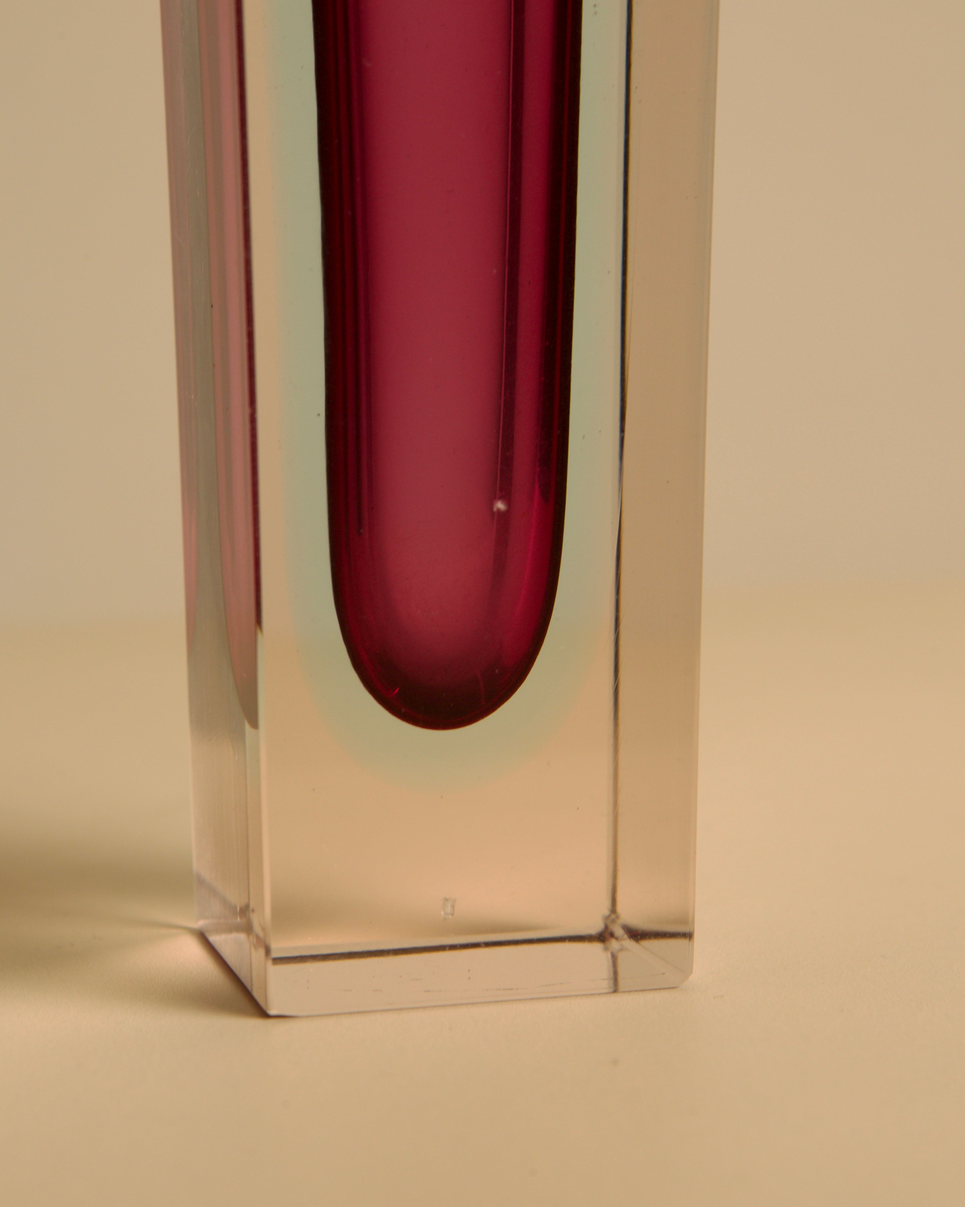 Close-up detail of red Murano glass vase showing clear crystal base