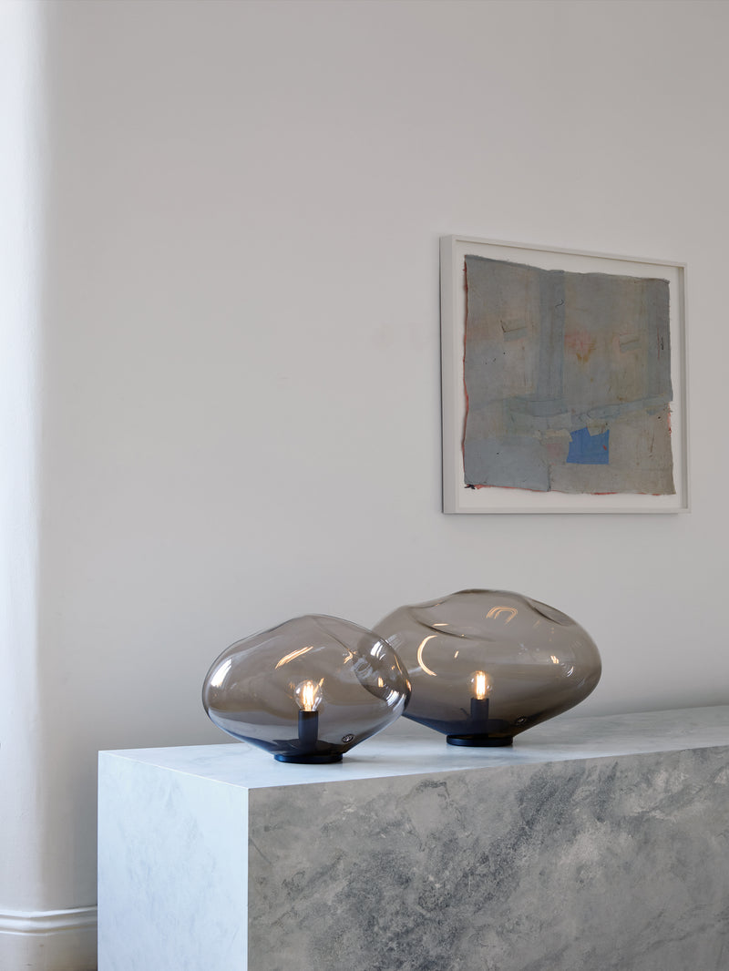 HAUMEA AMORPH table lamp - size S (L: 26cm), M (L: 32cm), L (L: 40cm), XL (L: 47cm) — close-up of smoky glass on marble surfa