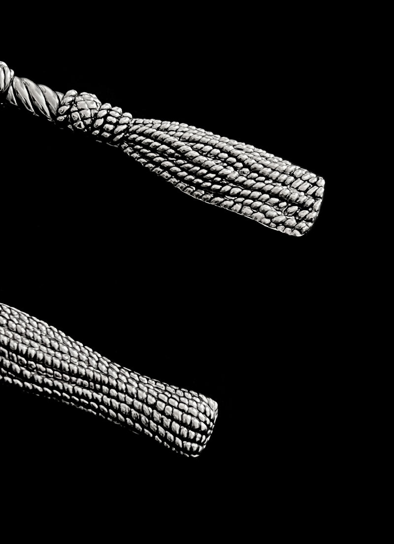 Silver-plated tassel cake servers detail view against black backdrop