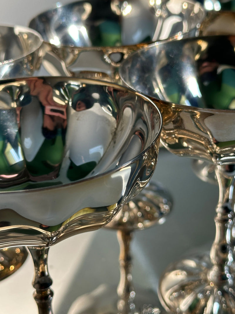 Close-up detail of silver-plated champagne coupes showing reflective surfaces