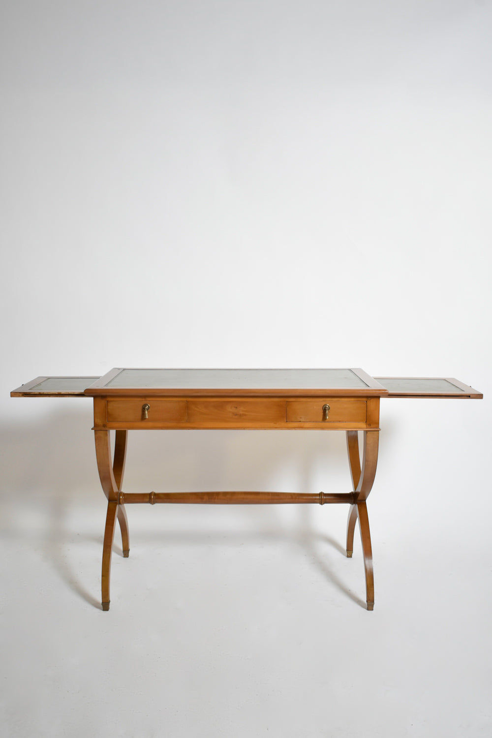 A 1970s Directoire style curule console table by Barracuda Interiors, featuring curved legs, a rectangular top with extendable leaves, and two front drawers, set against a plain white background.