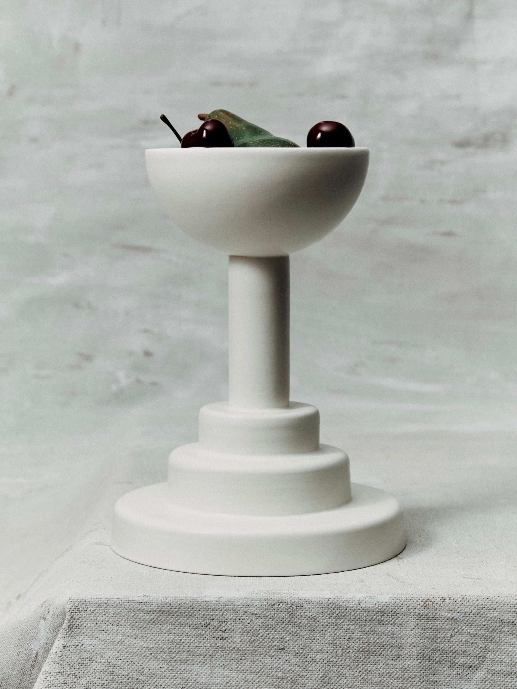 White glazed earthenware pedestal fruit bowl with cherries