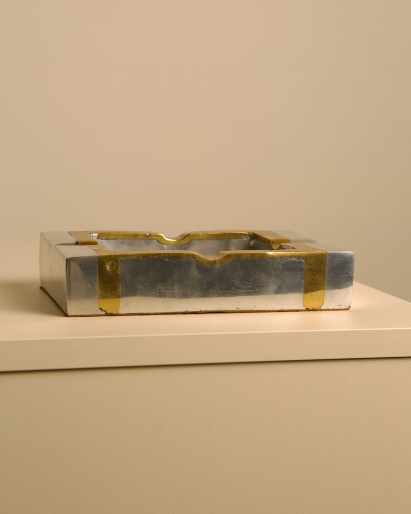Brutalist brass and silver ashtray detail view on white surface