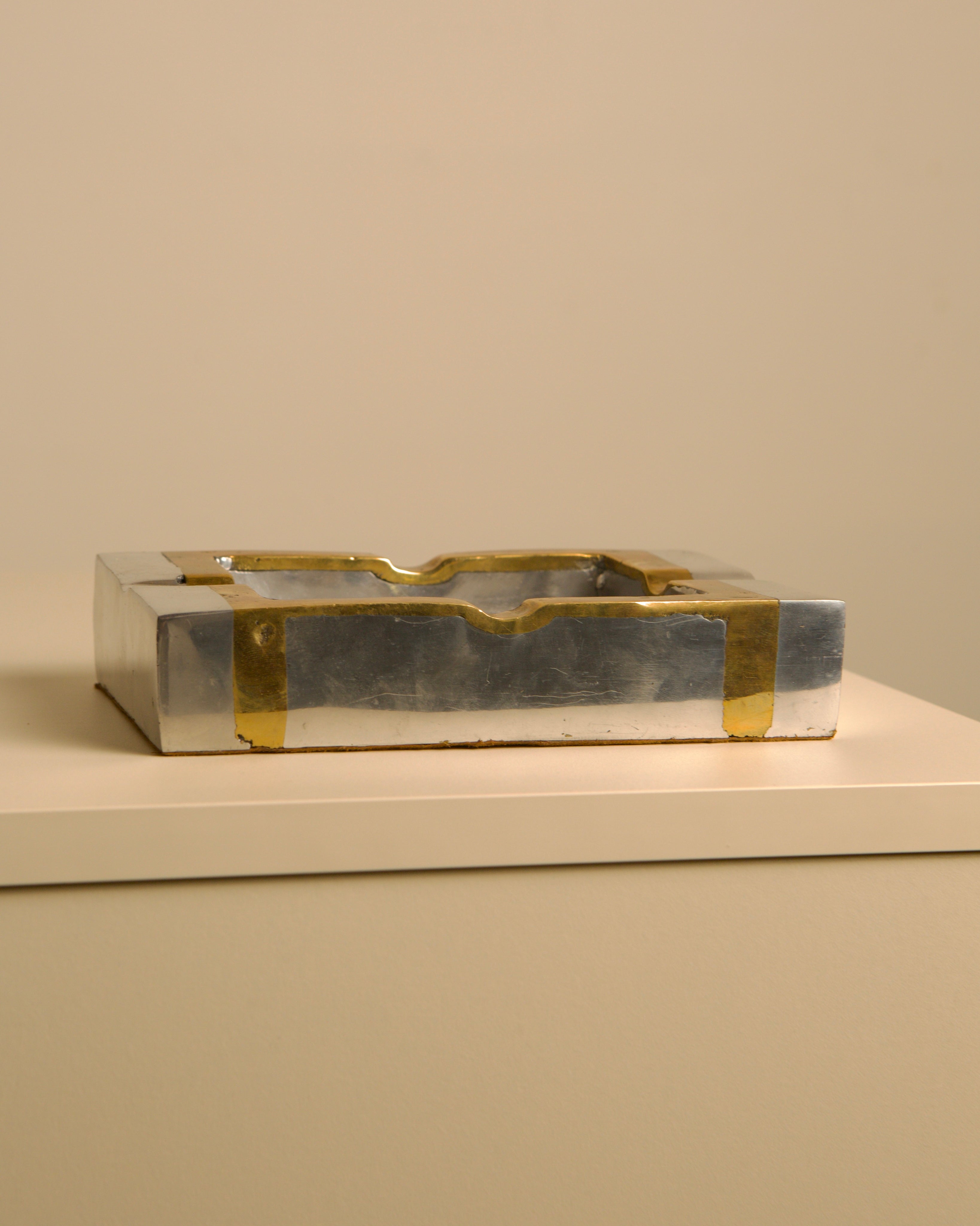 Brutalist brass and silver ashtray detail view on white surface