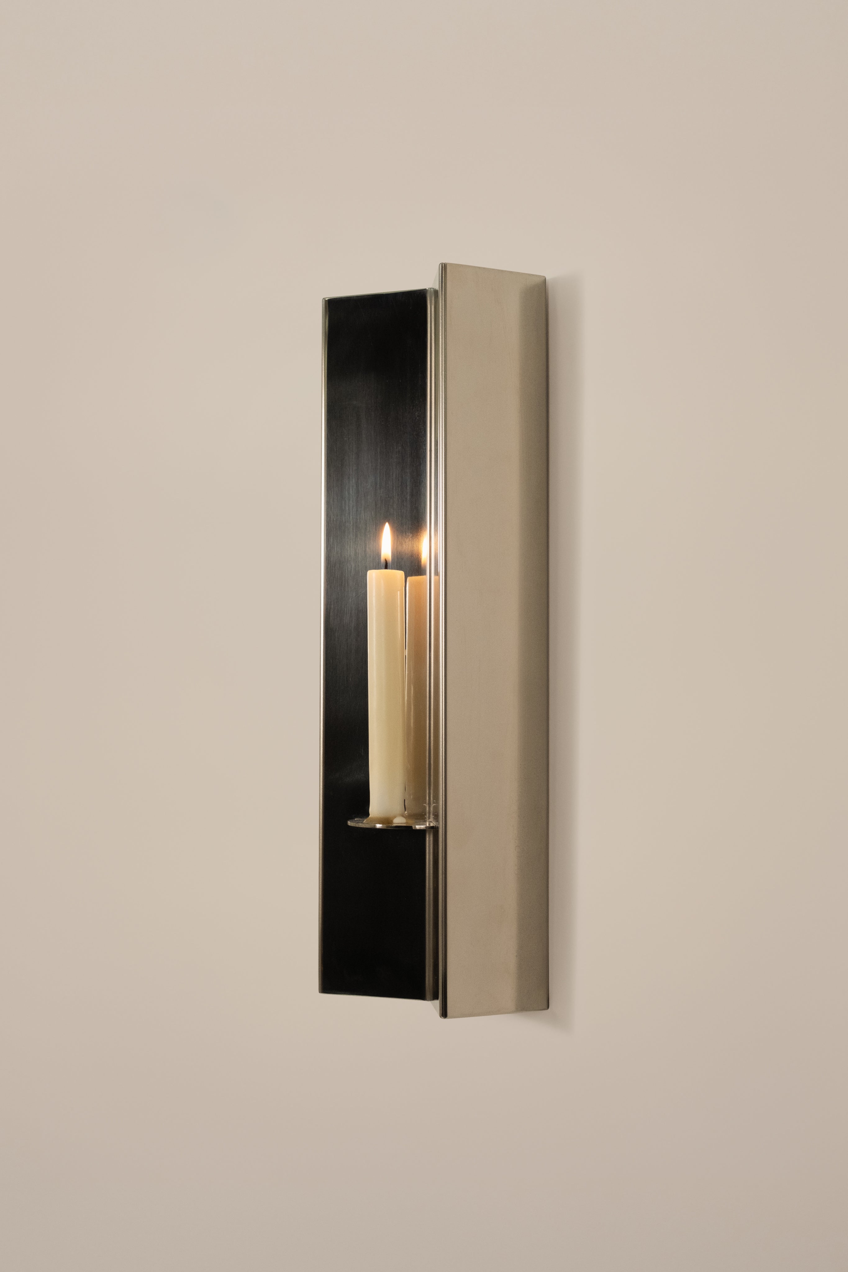 Arrow Candle Holder — close-up of polished metal with candle lit