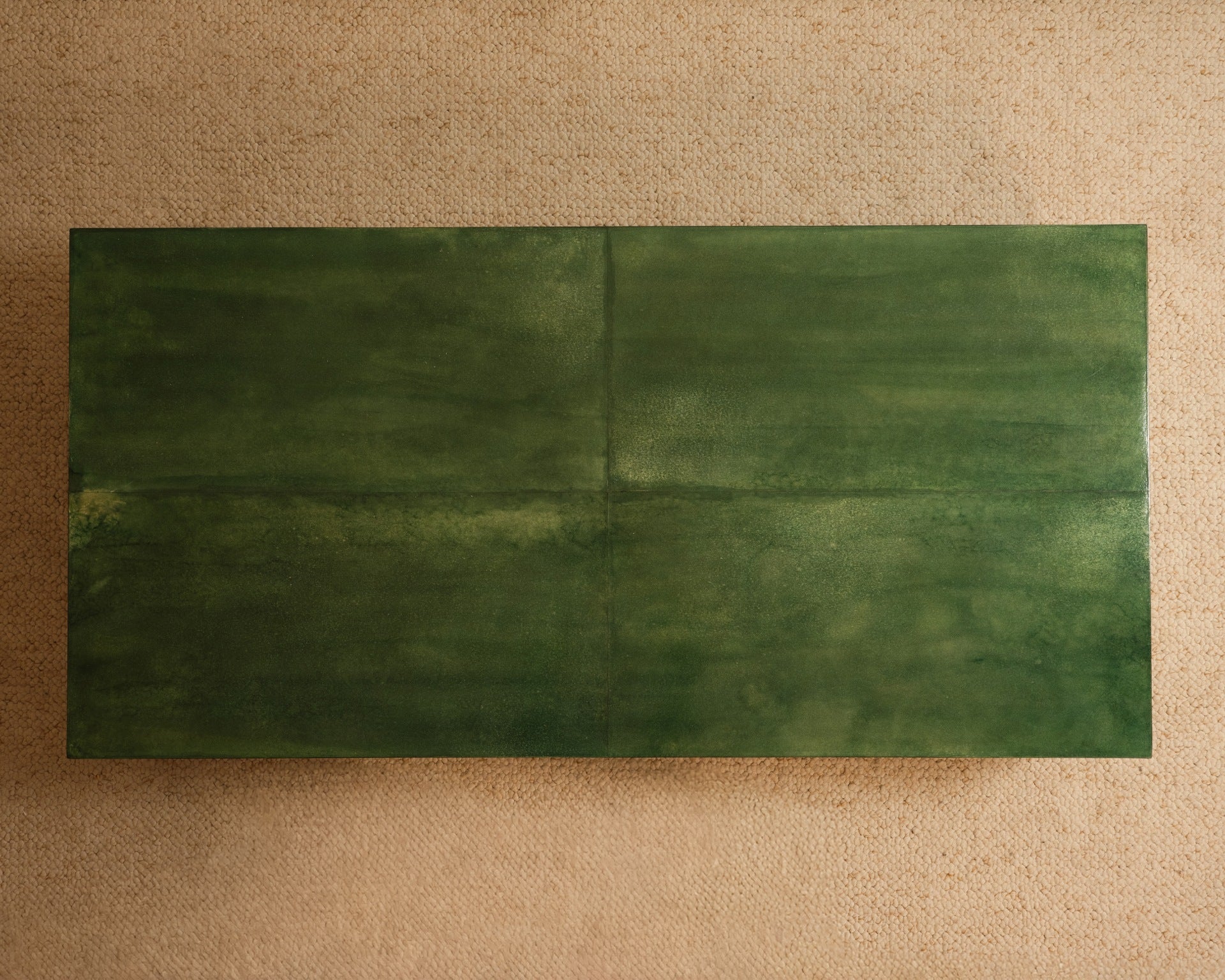 The Galerie Vauvart Green Parchment Table features a rectangular, dark green textured surface atop a beige, lightly speckled background, shown in an overhead view.