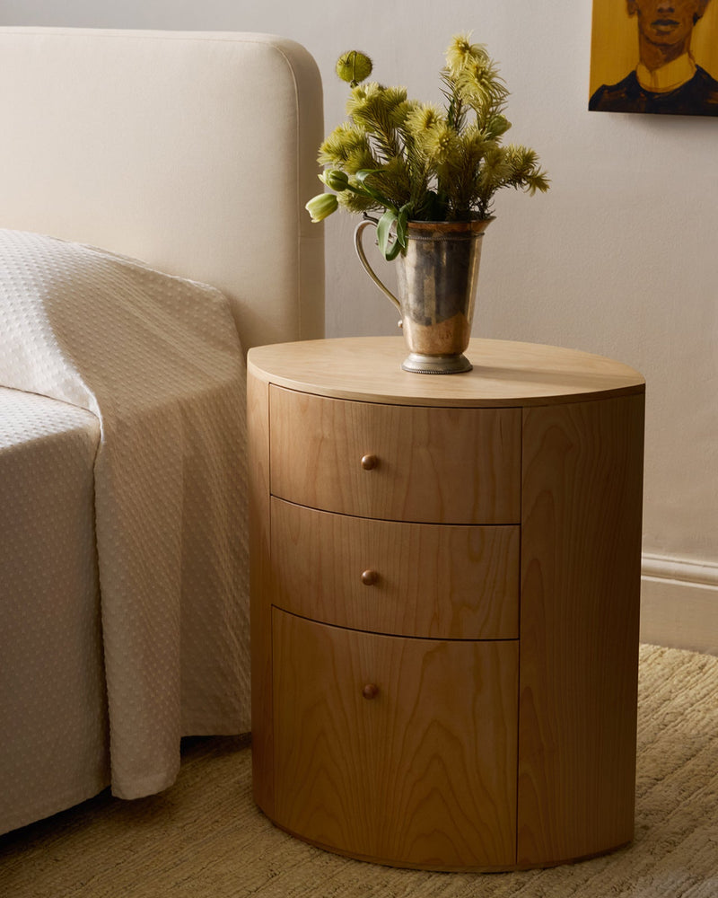 Observer nightstand in natural birch with three drawers styled beside cream armchair