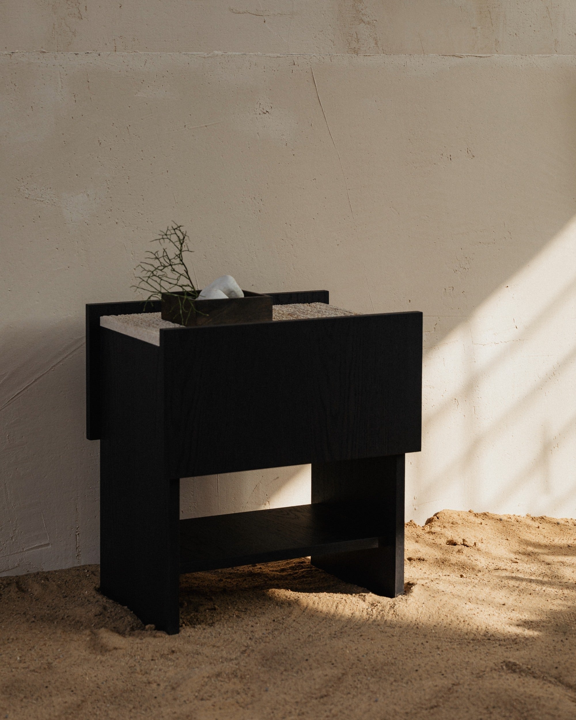 Black NOTO nightstand with geometric design on concrete floor