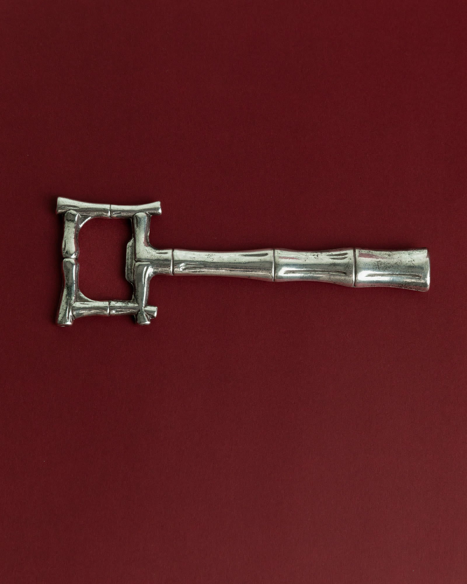 Vintage 1970s Silver Plated Bottle Opener, Bamboo Design — top view on red background