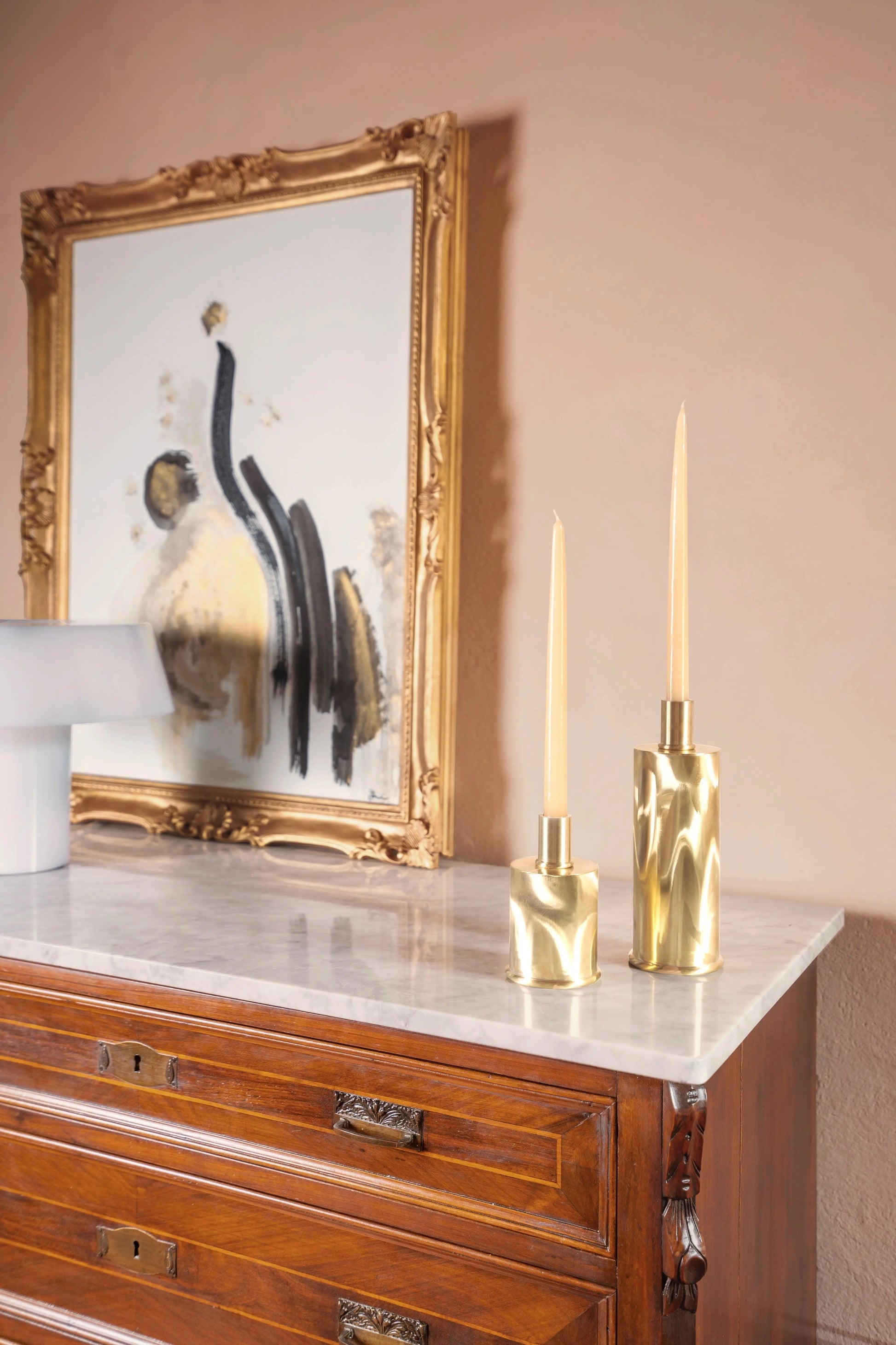 Tall Brushed Brass Candle Holders in Brushed natural brass — styled on marble surface with artwork background
