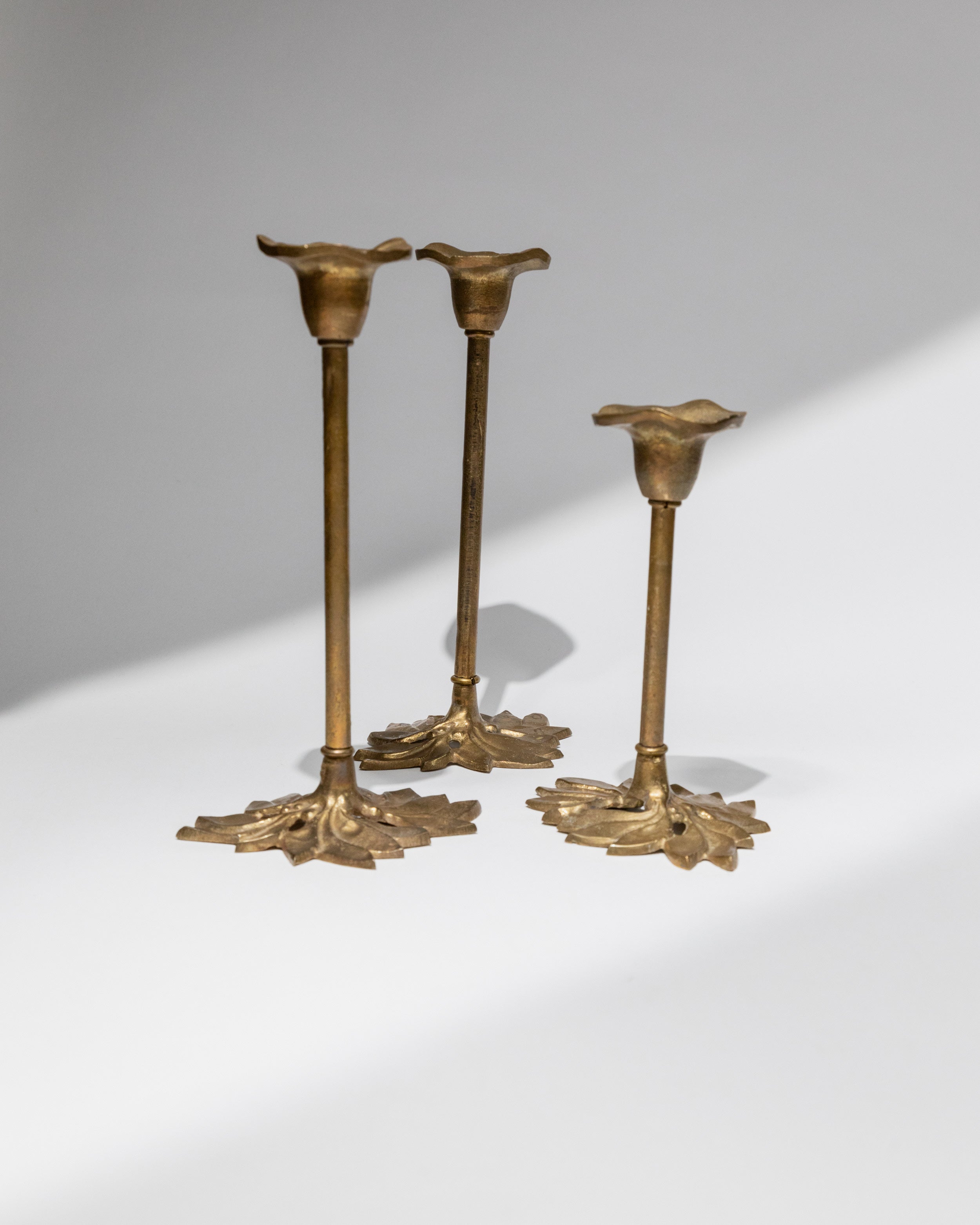 Set of three brass candle holders with ornate leaf bases, Italy 1940s