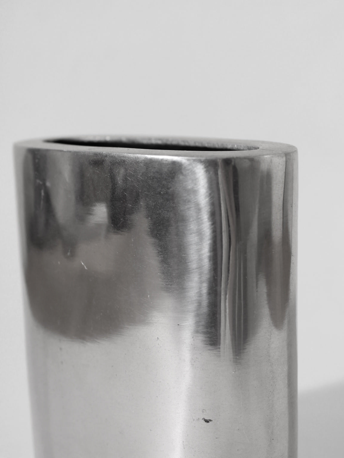 A close-up of the Polished Aluminum Square Flat Vase by Vintage Stories, showcasing its smooth, reflective surface and shiny finish, set against a plain light gray background for a classic 1960s-inspired look.