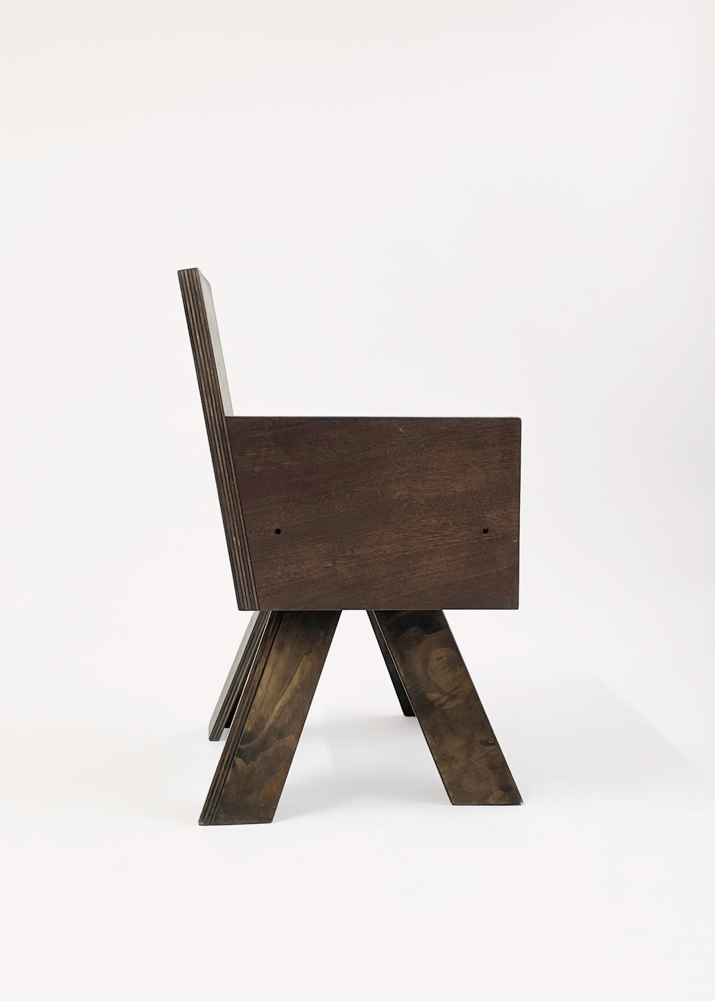 The End Table Chair by Goons from GOONS is a modern, minimalist wooden chair with a tall backrest and angled legs, shown in a side view against a plain white background.
