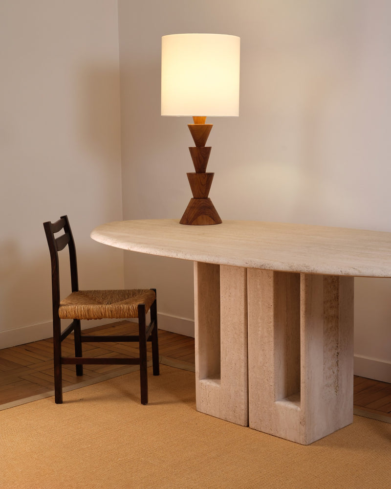 Graphic wooden table lamp with stacked triangular base on travertine desk