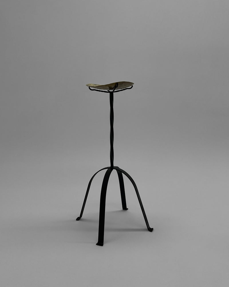 Minimalist iron candle holder with curved tripod legs by Camille Tan