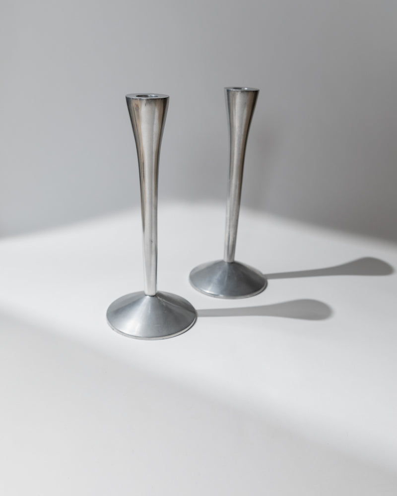 Pair of sleek stainless steel candlesticks casting shadows