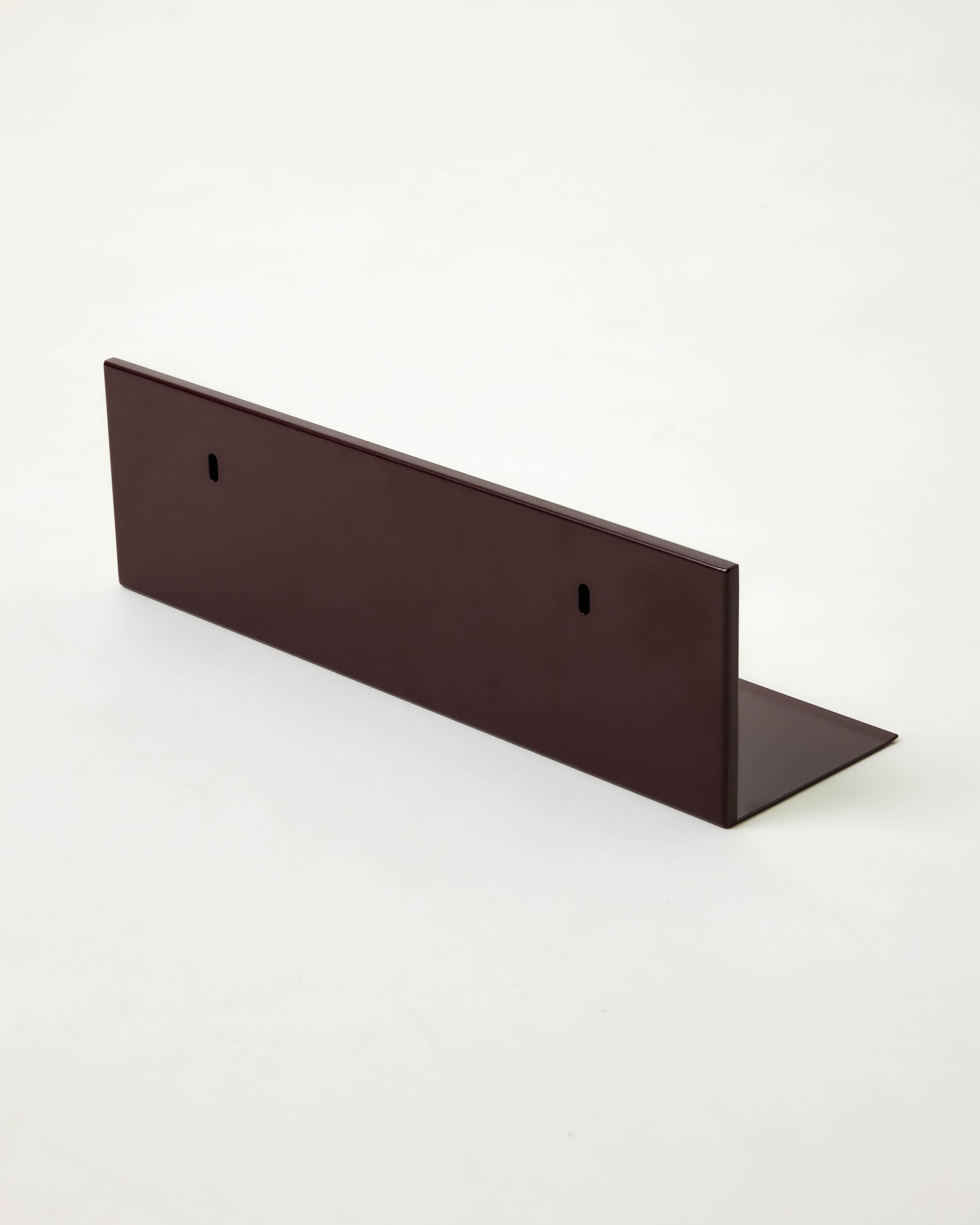 The Dot Objects Mirror Steel Shelf is a dark brown, L-shaped steel shelf with a minimalist design and two small vertical slots on the upright side, shown against a plain white background.